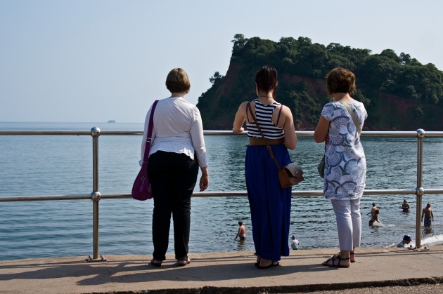 Three ladies watch the sea in Teignmouth.